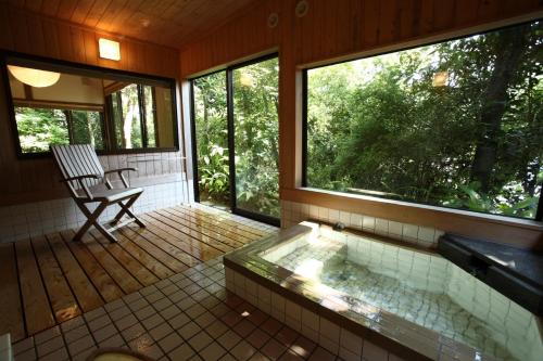 La salle de bains est pourvue d'une baignoire et d'une chaise sur une terrasse couverte. dans l'établissement Onsensui Pool & Fufu Rotenburo no Hanareyado Yurian, à Ibusuki