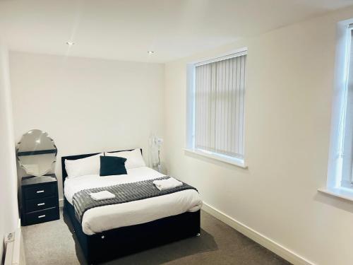 a white bedroom with a bed and two windows at Doncaster 2 Bedroom Luxury Apartment in Doncaster