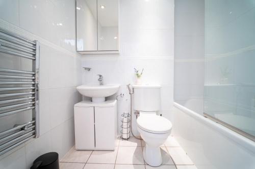 a white bathroom with a toilet and a sink at Cozy 2BR Apt in Greenwich, Near O2 Arena and Excel, Fast Wi-Fi, Free Parking, Excellent links Elizabeth and Southeastern Line in London