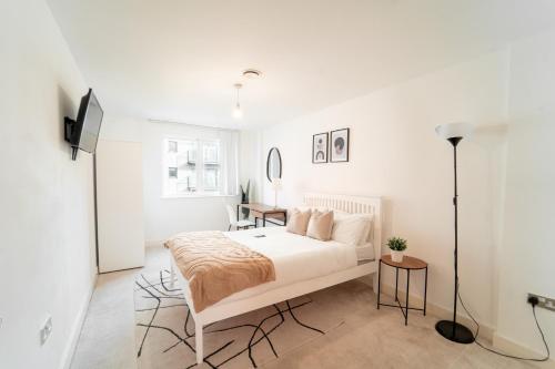 a white bedroom with a bed and a desk at Cozy 2BR Apt in Greenwich, Near O2 Arena and Excel, Fast Wi-Fi, Free Parking, Excellent links Elizabeth and Southeastern Line in London