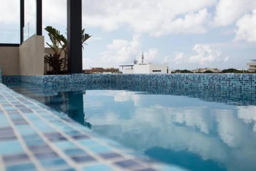 a swimming pool with blue tiles on a building at Beachside Studio & Jacuzzi Bliss in Playa del Carmen
