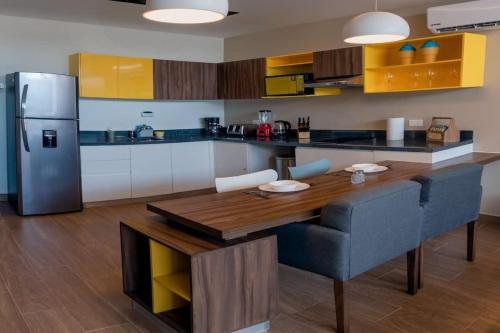 a kitchen with a wooden table and a refrigerator at Beachside Studio & Jacuzzi Bliss in Playa del Carmen