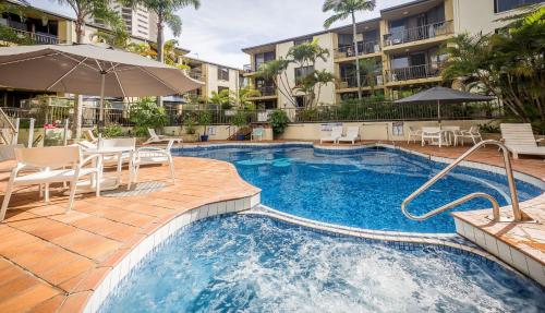 a pool with chairs and umbrellas in a hotel at Aussie Resort in Gold Coast