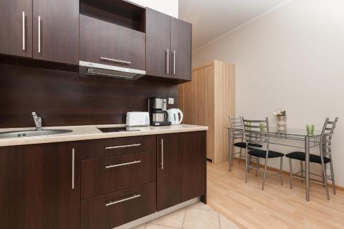 uma cozinha com armários de madeira, um lavatório e cadeiras em Apartamenty Regina Maris em Świnoujście