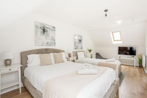 a bedroom with two beds and a flat screen tv at Comfortable 4 Bed Modern Townhouse with Parking in Long Eaton