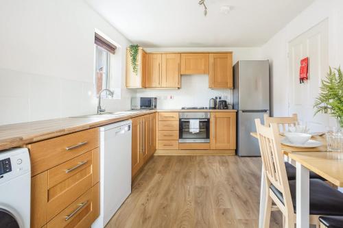 a kitchen with wooden cabinets and a wooden table at Comfortable 4 Bed Modern Townhouse with Parking in Long Eaton