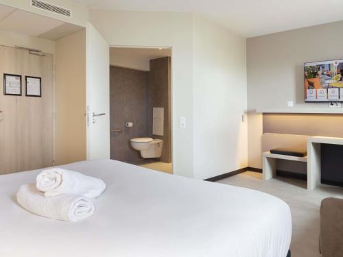 a hotel room with a white bed and a toilet at ibis Douai Dechy in Dechy