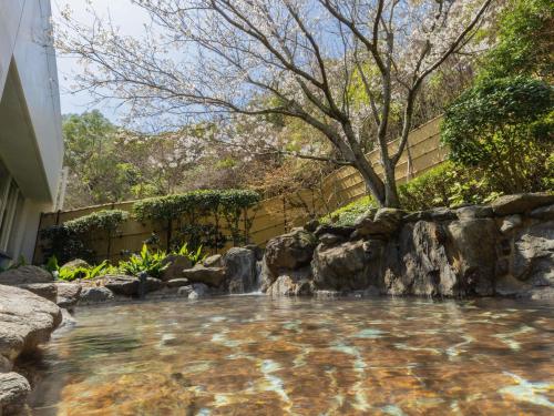 a pool of water with a waterfall in a backyard at Mercure Fukuoka Munakata Resort & Spa in Munakata