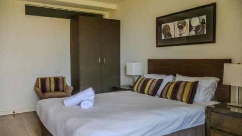 a bedroom with a large white bed and a chair at Resort Apartment 275 in Torquay