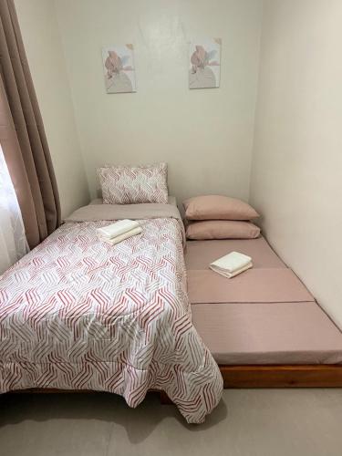 a small bedroom with a bed with pink and white sheets at The Eastcape by Akeisha in Bacolod