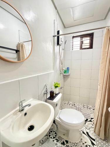 a bathroom with a sink and a toilet and a mirror at The Eastcape by Akeisha in Bacolod