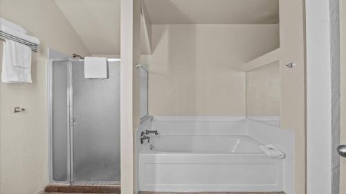 a white bathroom with a tub and a shower at Red Arrow Inn & Suites, a Travelodge by Wyndham in Montrose