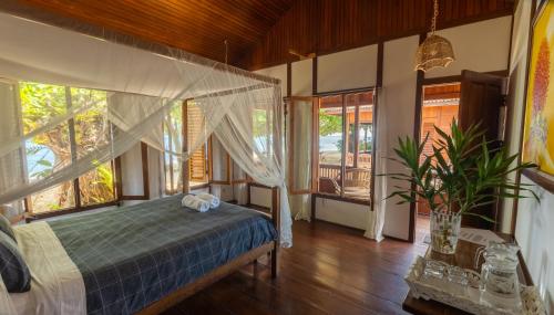 a bedroom with a bed in a room with windows at Bobocha Siladen Boutique Resort in Bunaken