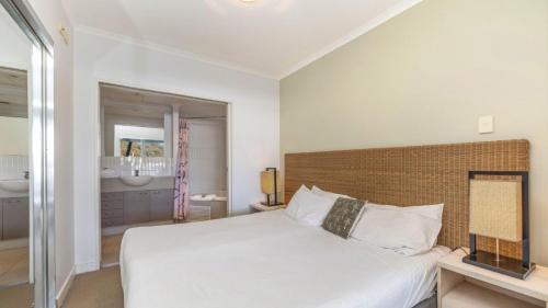 a bedroom with a white bed and a bathroom at Pool Delight - Ettalong Beach Resort in Ettalong Beach