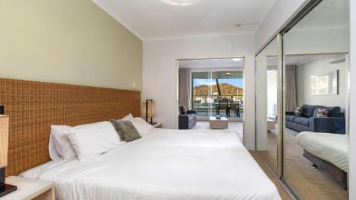 a bedroom with a large bed and a living room at Pool Delight - Ettalong Beach Resort in Ettalong Beach
