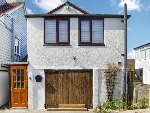 a white house with a wooden garage door at Angie's Beachside House in Saint Osyth