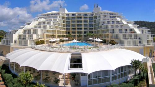 a large white building with a pool in front of it at Seashells - Ettalong Beach Resort in Ettalong Beach