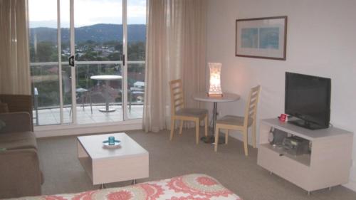 a living room with a television and a table with chairs at Seashells - Ettalong Beach Resort in Ettalong Beach