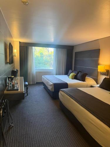 a hotel room with two beds and a window at Hotel Real Alameda de Queretaro in Querétaro
