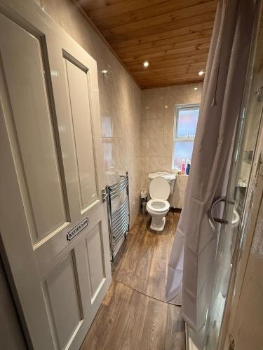a bathroom with a toilet and a window and a door at Near city centre, Derby train station and royal Derby hospital in Derby