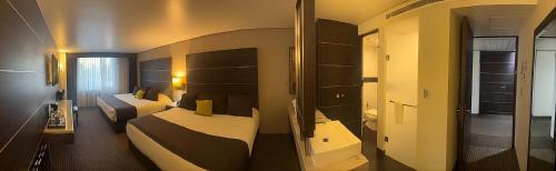 a hotel room with two beds and a mirror at Hotel Real Alameda de Queretaro in Querétaro