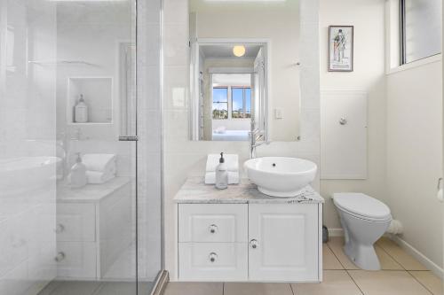 a white bathroom with a sink and a toilet at Yulunga 20 in Mooloolaba