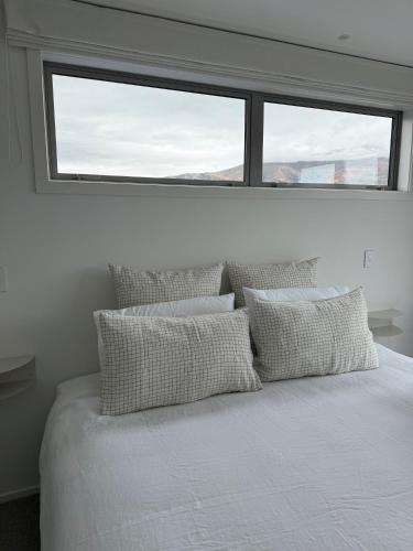 a bedroom with a bed with pillows and a window at McNeil Luxury Studio in Wanaka