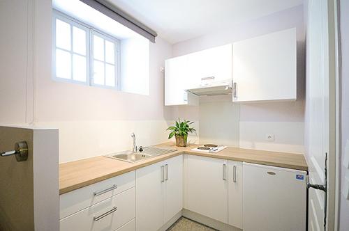 cocina con armarios blancos, fregadero y ventana en Les appartements du Relais du Jacquet, en Navarrenx