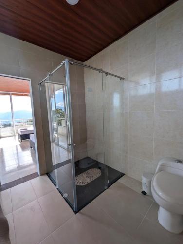 a bathroom with a glass shower with a toilet at Hotel Campestre El Alcazar in Moniquirá