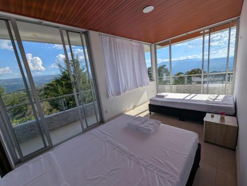 a bedroom with two beds and a large window at Hotel Campestre El Alcazar in Moniquirá