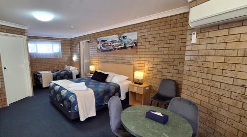 a hotel room with two beds and a table and chairs at Macintyre Motor Inn in Goondiwindi