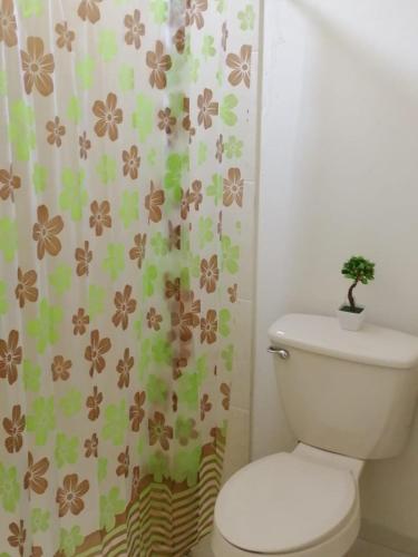 a bathroom with a toilet with a flower shower curtain at VENECIA APARTMENT, Excellent Location in Tepic