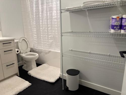 a bathroom with a toilet and a shelf with towels at 5 Star Suite with Free Parking and Easy Access to Downtown in Calgary