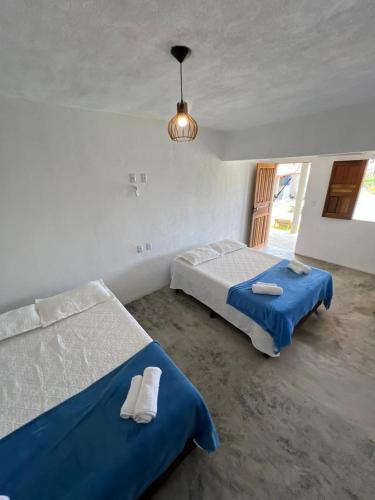 a bedroom with two beds and a chandelier at Suite Adam 3 em Caraíva com piscina 900m da Vila in Caraíva