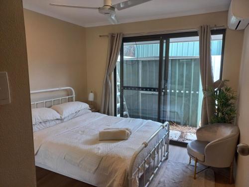 a bedroom with a bed and a chair and a window at Peaceful and private two bedroom unit in Alice Springs