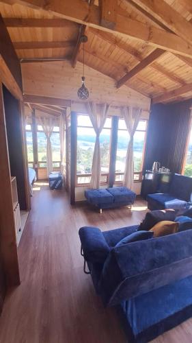 a large living room with blue couches and large windows at Glamping La Villa in Guatavita
