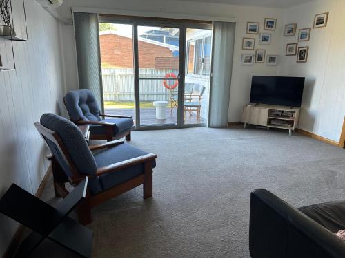 a living room with two chairs and a television at The Boat House in Strahan