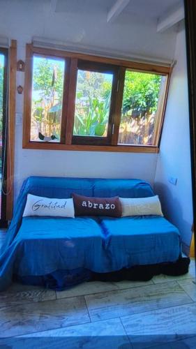a blue bed in a room with two windows at Piccolo Casa de playa La caleta in Mar de Cobo