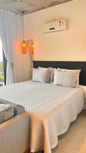 a bedroom with a bed with a white comforter at Pousada Studio Siriú in Garopaba