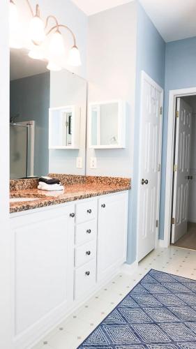 a bathroom with white cabinets and a sink and a mirror at The Cozy Hub in Simpsonville