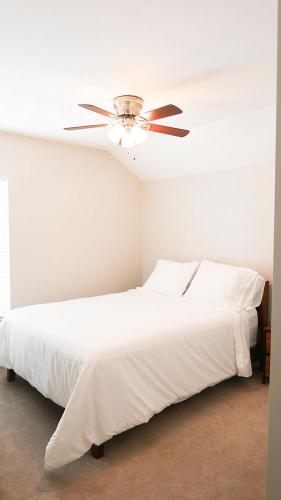 a bedroom with a white bed with a ceiling fan at The Cozy Hub in Simpsonville