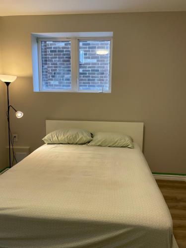ein Bett in einem Schlafzimmer mit Fenster in der Unterkunft New Basement Apartment unit sleeps 4 in Oakville