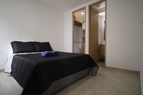 a bedroom with a black bed with a blue towel on it at Praseo in Serena del Mar