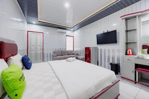 a bedroom with a large white bed and a flat screen tv at Urbanview Hotel Executive Residence Semarang by RedDoorz in Candi