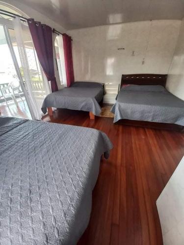 a bedroom with two beds and a wooden floor at Lotus Appartementen Nickerie in Majoor Fernandes