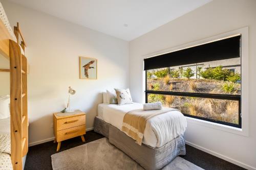 a bedroom with a bed and a large window at Blackwood Lakeview Retreat in Queenstown