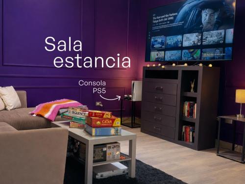 a living room with a purple wall with a tv at Casa Morada in Ciudad Juárez
