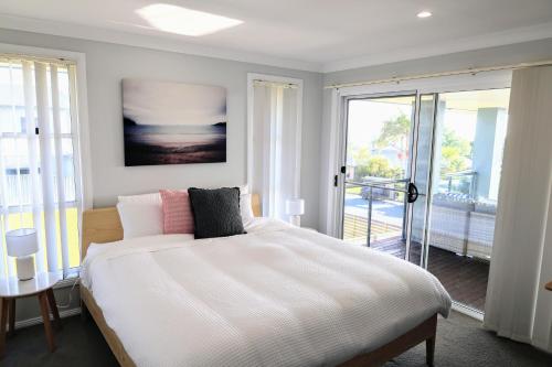 a bedroom with a large bed and a balcony at Diamond Beach Getaway - Diamond Beach in Diamond Beach