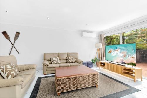 a living room with a couch and a flat screen tv at Paradise Waters 13 in Coffs Harbour