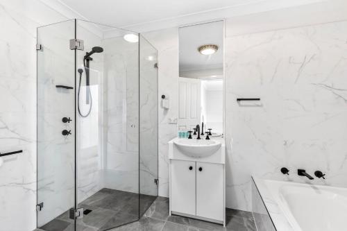 a white bathroom with a sink and a shower at Paradise Waters 13 in Coffs Harbour